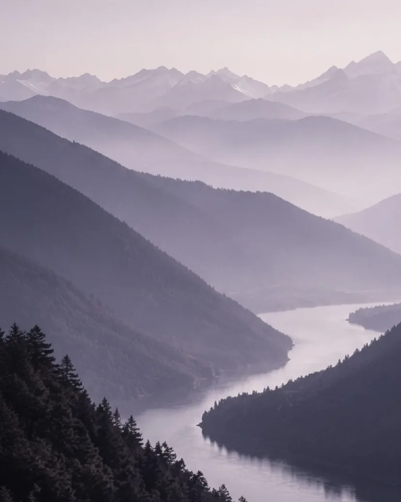 Bergketten im Nebel, das Licht wird über den Gipfeln heller.