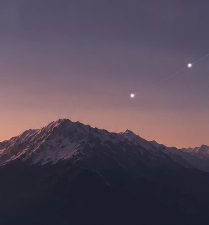 In der Dämmerung stehen zwei helle Sterne, durch eine feine Lichtspur verbunden, über einem verschneiten Bergkamm.