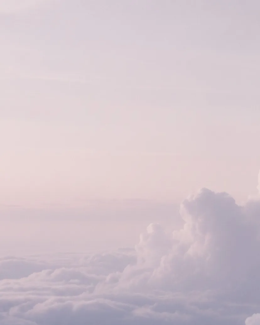 Über einer dichten Wolkendecke öffnet sich ein weiter, lavendelfarbener Himmel.